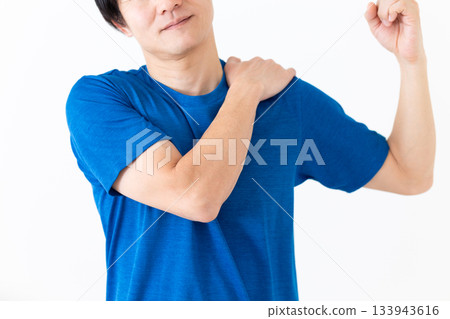 A middle-aged man in a T-shirt doing shoulder stretching exercises 133943616