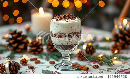 A festive dessert in a glass with cream and chocolate shavings, amidst pinecones, cinnamon, and warm lights 133944768