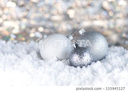 Silver Christmas ornaments on snow with glitter and soft bokeh lighting in a festive winter scene 133945127