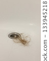 Water drain hole is clogged with long hair clump. Close-up.  133945218