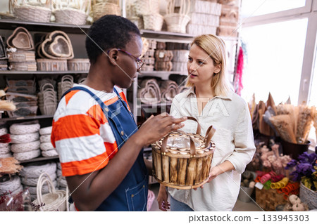 Shop assistant showing wicker basket to customer in a store 133945303