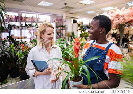 Florist showing a plant to a customer in a flower shop 133945306