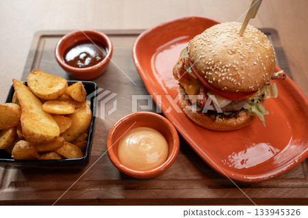 Savoring a delicious gourmet burger and crispy potatoes at a cozy restaurant 133945326