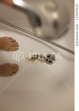 Water drain hole is clogged with long hair clump after woman taken shower. Selective focus. Water drain hole is clogged with long hair clump after woman taken shower. Selective focus. 133945625
