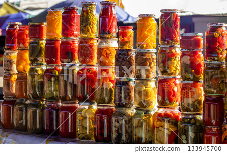 Colorful jars of pickled vegetables stacked on a market stall create a vibrant display 133945700