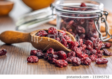 Tasty dried cranberries in scoop on wooden table. 133945732
