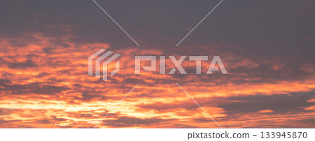 Vibrant sunset sky over the horizon with orange clouds and warm glow at dusk Vibrant sunset sky over the horizon with orange clouds and warm glow at dusk 133945870
