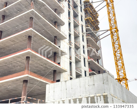 Urban building site, Industrial urban high rise under construction with machinery and exposed framework 133947335