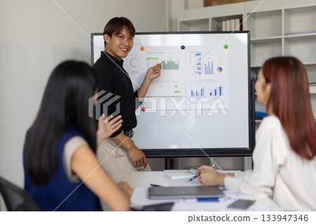 Asian businessman leading meeting with presentation on whiteboard. Asian businessman leading meeting with presentation on whiteboard. 133947346