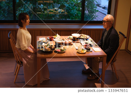 在一家旅館裡，一對父母和孩子享用輕鬆的晚餐。 133947651