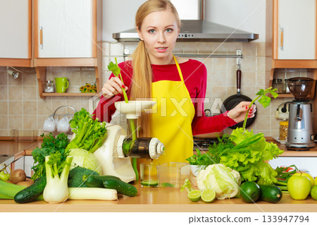 Woman in kitchen making vegetable smoothie juice 133947794