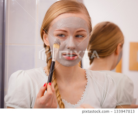 Woman applying with brush clay mud mask to her face Woman applying with brush clay mud mask to her face 133947813