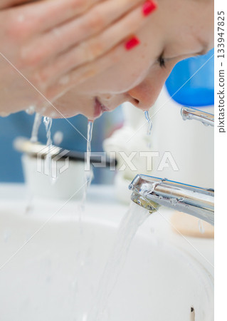 Woman washing face in bathroom. Hygiene. Woman washing face in bathroom. Hygiene. 133947825