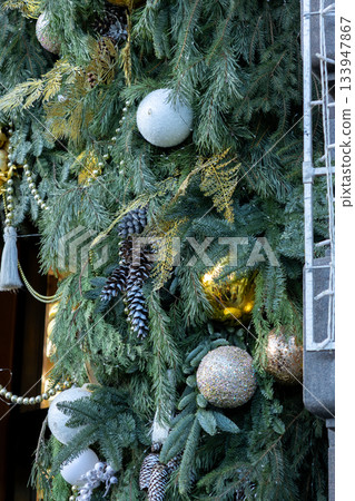 Christmas tree with many ornaments and pine cones. 133947867