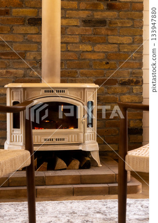 Brick fireplace with a wood burning stove and two chairs.  133947880