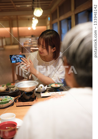 一位家長和孩子在日本餐廳用餐時拍照的場景 133948142