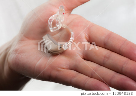 senior person holding hearing aid closeup senior person holding hearing aid closeup 133948188