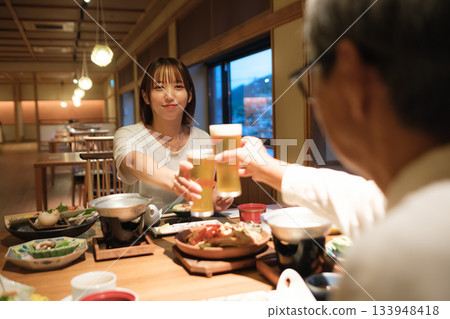 在傳統客棧裡，一家人共進晚餐，舉杯慶祝，場面溫馨感人。 133948418