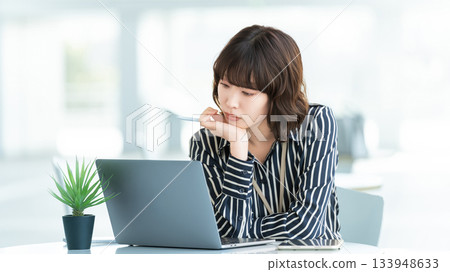 一位女商人一邊用電腦一邊思考 133948633