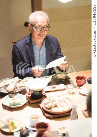 A senior couple enjoys dinner at a traditional Japanese inn while looking at the menu. 133948658
