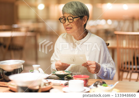 A senior couple enjoys dinner at a traditional Japanese inn while looking at the menu. 133948660