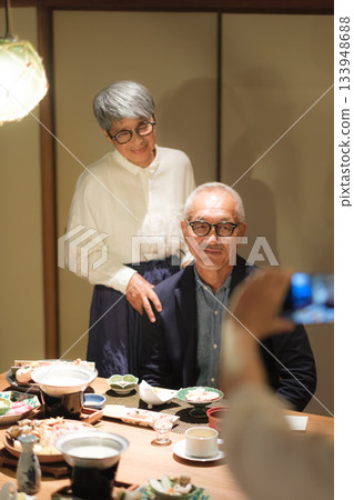 一對老年夫婦在家庭旅行途中,於家庭聚餐上,請女兒為他們拍攝一張紀念60歲生日的照片。 一對老年夫婦在家庭旅行途中,於家庭聚餐上,請女兒為他們拍攝一張紀念60歲生日的照片。 133948688