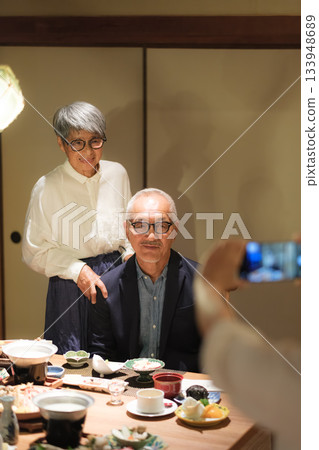 一對老年夫婦在家庭旅行途中,於家庭聚餐上,請女兒為他們拍攝一張紀念60歲生日的照片。 一對老年夫婦在家庭旅行途中,於家庭聚餐上,請女兒為他們拍攝一張紀念60歲生日的照片。 133948689