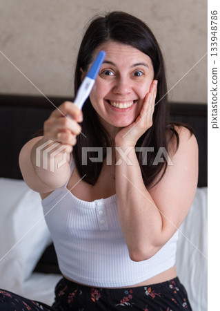 Surprised Woman with Positive Pregnancy Test 133948786