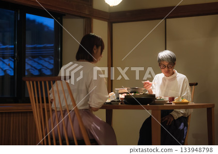 A mother and daughter celebrate their 60th birthday on a trip. The two share a warm moment over a quiet dinner at a traditional Japanese inn. 133948798