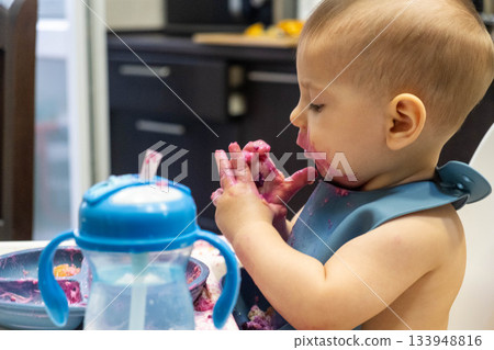 Baby Enjoying a Messy Meal in High Chair 133948816