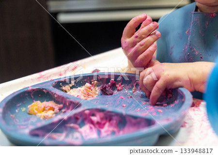 Baby Enjoying a Messy Meal in High Chair Baby Enjoying a Messy Meal in High Chair 133948817