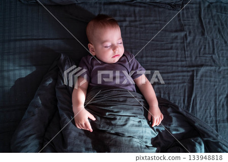 Peaceful baby sleeping on a dark bed 133948818