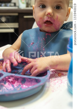 Baby Enjoying a Messy Meal in High Chair 133948819