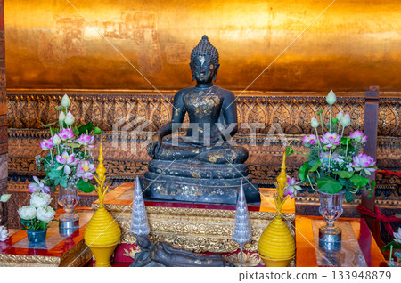 Small Buddha statues inside Wat Pho temple in Bangkok, Thailand, arranged in a graceful line that highlights their golden tones, calm expressions, and traditional spiritual atmosphere. 133948879