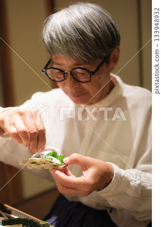 一對老年夫婦在慶祝60歲生日的旅途中，於一家傳統的日本旅館悠閒地享用晚餐。 133948932