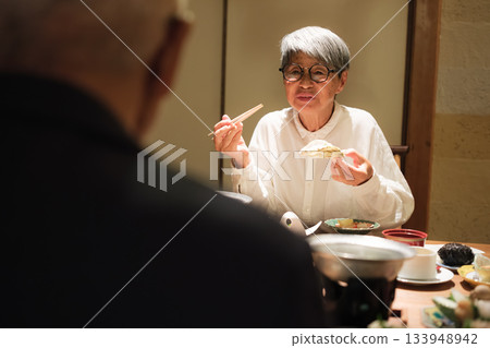 A senior couple enjoying a leisurely dinner at a traditional Japanese inn on a trip to celebrate their 60th birthday. A senior couple enjoying a leisurely dinner at a traditional Japanese inn on a trip to celebrate their 60th birthday. 133948942