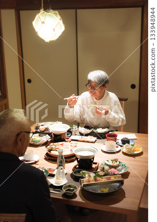 A senior couple enjoying a leisurely dinner at a traditional Japanese inn on a trip to celebrate their 60th birthday. A senior couple enjoying a leisurely dinner at a traditional Japanese inn on a trip to celebrate their 60th birthday. 133948944