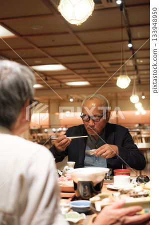 A senior couple enjoying a leisurely dinner at a traditional Japanese inn on a trip to celebrate their 60th birthday. A senior couple enjoying a leisurely dinner at a traditional Japanese inn on a trip to celebrate their 60th birthday. 133948950