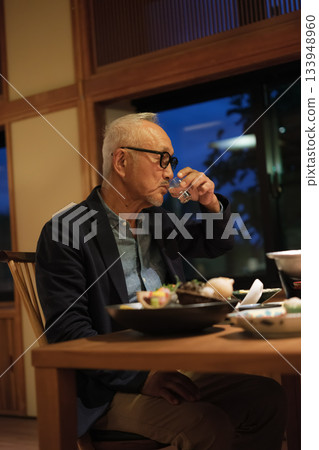 一對老年夫婦在慶祝60歲生日的旅途中，於一家傳統的日本旅館悠閒地享用晚餐。 133948960