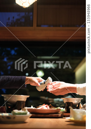 A senior couple enjoying a leisurely dinner at a traditional Japanese inn on a trip to celebrate their 60th birthday. A senior couple enjoying a leisurely dinner at a traditional Japanese inn on a trip to celebrate their 60th birthday. 133948966