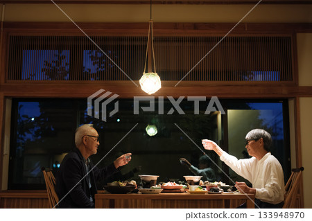 一對老年夫婦在慶祝60歲生日的旅途中，於一家傳統的日本旅館悠閒地享用晚餐。 133948970