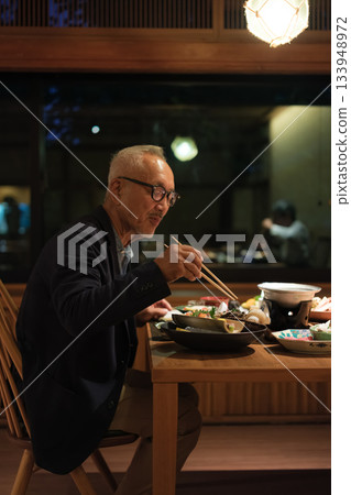 A senior couple enjoying a leisurely dinner at a traditional Japanese inn on a trip to celebrate their 60th birthday. A senior couple enjoying a leisurely dinner at a traditional Japanese inn on a trip to celebrate their 60th birthday. 133948972