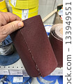 Hand holding sandpaper roll in hardware store aisle for DIY projects 133949551