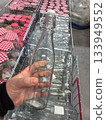 Clear glass bottle held by a shopper in a store full of jars 133949552