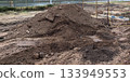 Construction site with a large mound of dirt and heavy machinery tracks 133949553