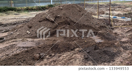 Construction site with a large mound of dirt and heavy machinery tracks 133949553
