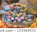 Brightly colored candies shaped like speckled eggs fill a clear glass bowl 133949555