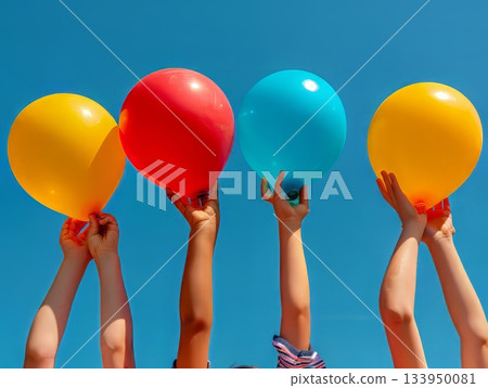 Colorful balloons in children's hands against blue summer sky 133950081
