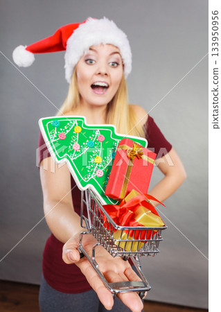 Santa woman holding shopping cart with christmas gifts 133950956