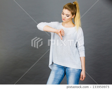 Sad woman showing thumb down gesture 133950973